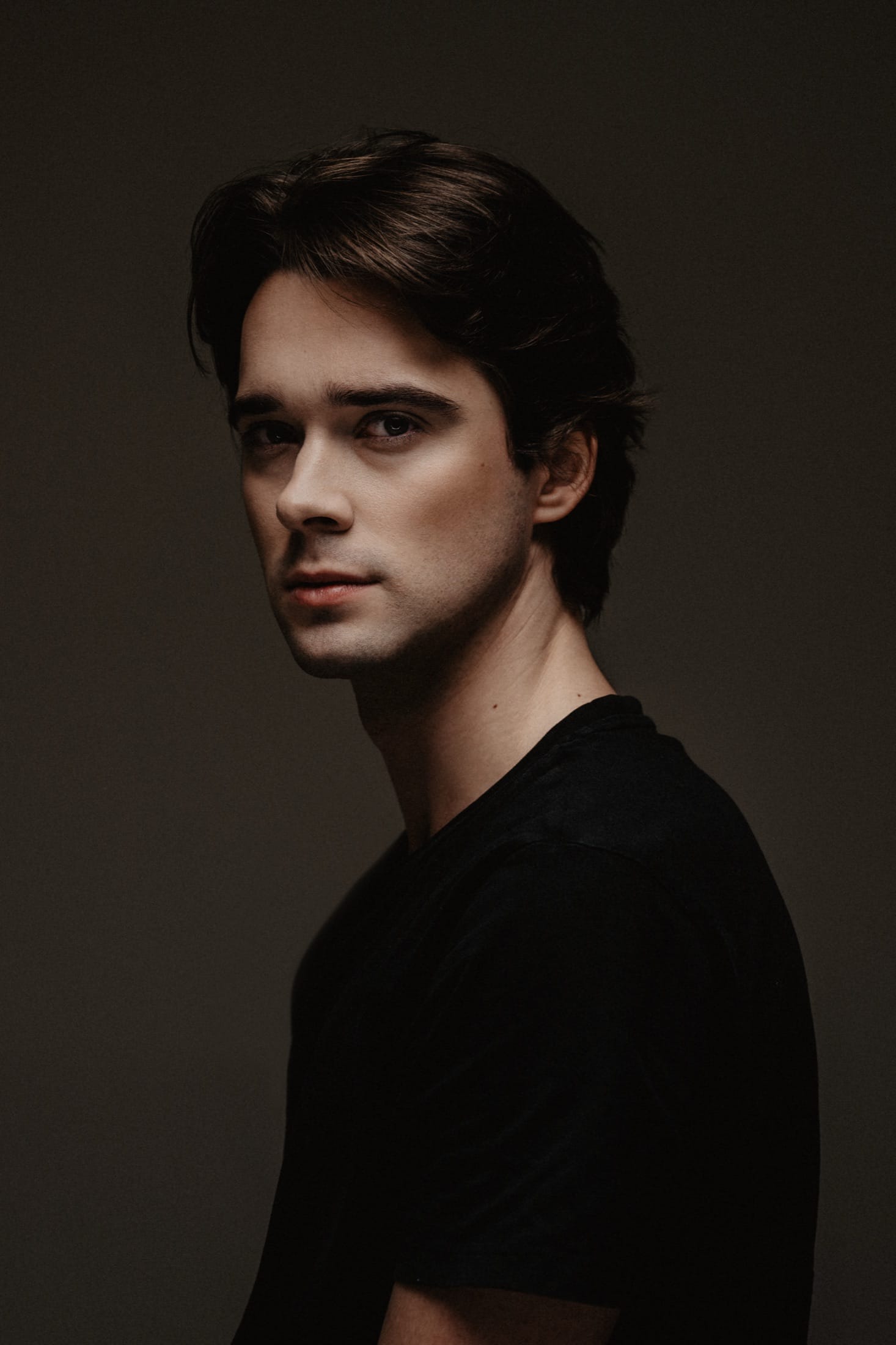 Portrait of Vojtech Babista in a black t-shirt against a dark studio background